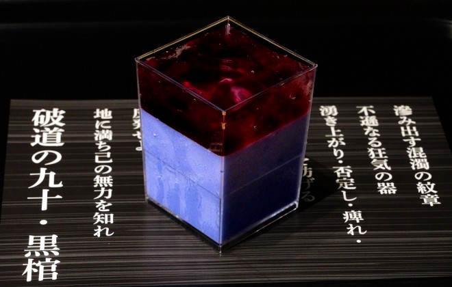 The “Hadō No. 90: Kurohitsugi Pudding” served at BLEACH WORLD features a dark purple milk pudding layered with blueberry sauce and clear jelly—presented atop a printed incantation sheet
