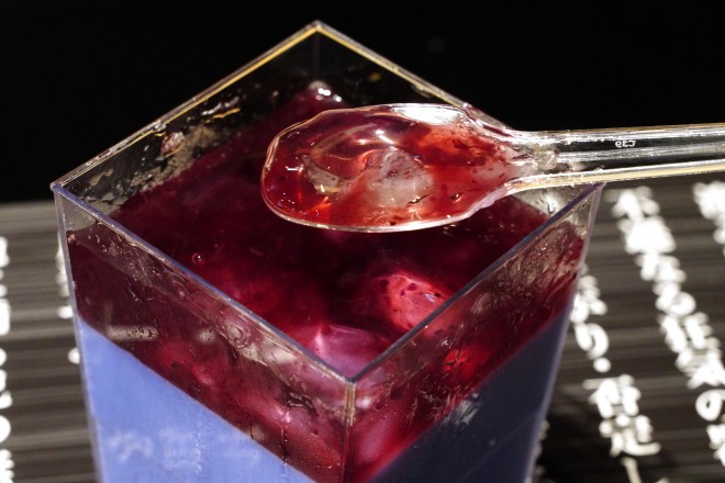 The “Hadō No. 90: Kurohitsugi Pudding” served at BLEACH WORLD features a dark purple milk pudding layered with blueberry sauce and clear jelly—presented atop a printed incantation sheet